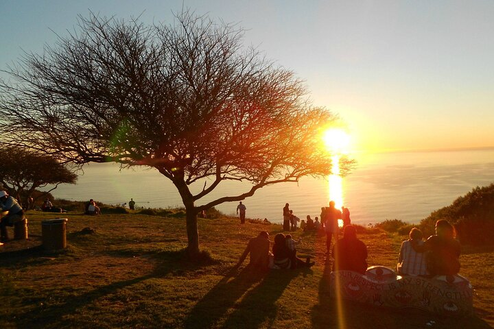 Witness the stunning sunset over the Atlantic Ocean as you relax with friends enjoying a picnic on Signal Hill while Cape Town transforms in the warm glow of twilight.